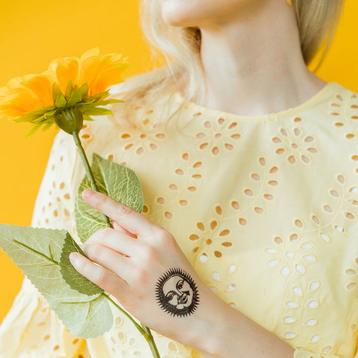 Black And White Vintage Sun Face Tattly Temporary Tattoo On A Person's Hand